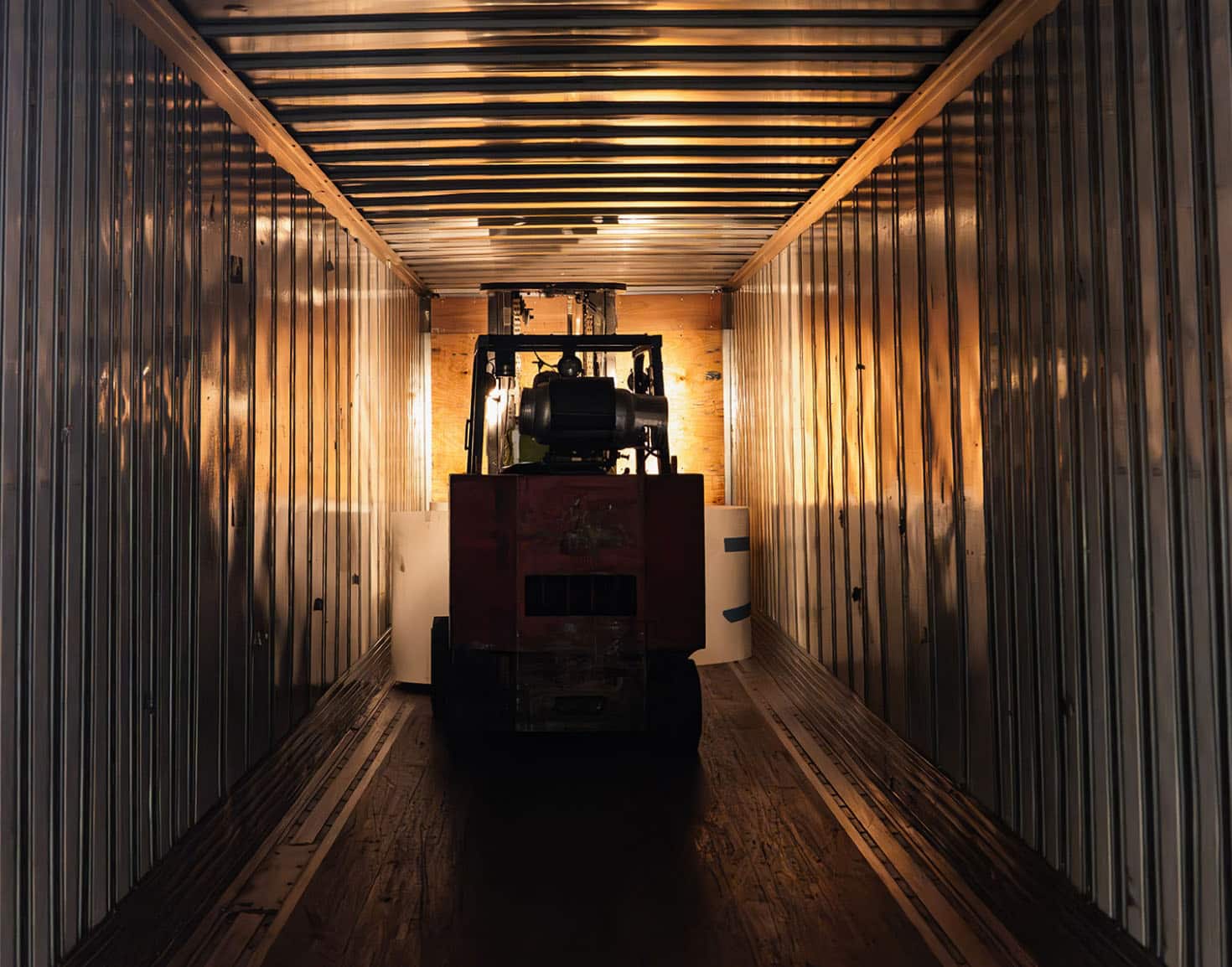 Forklift moving materials into a shipping container